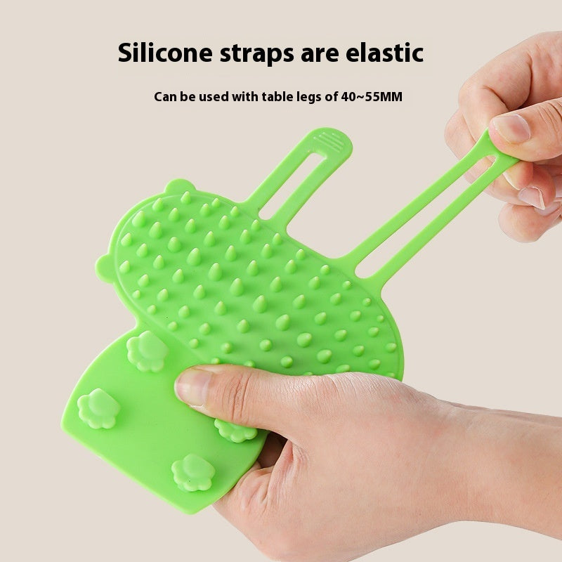 Silicone cat grooming brush wrapped around table leg for scratching and massage