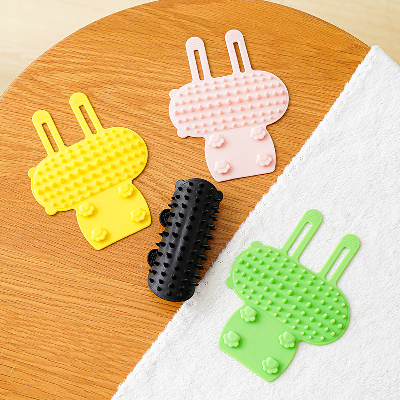 Silicone cat grooming brush wrapped around table leg for scratching and massage